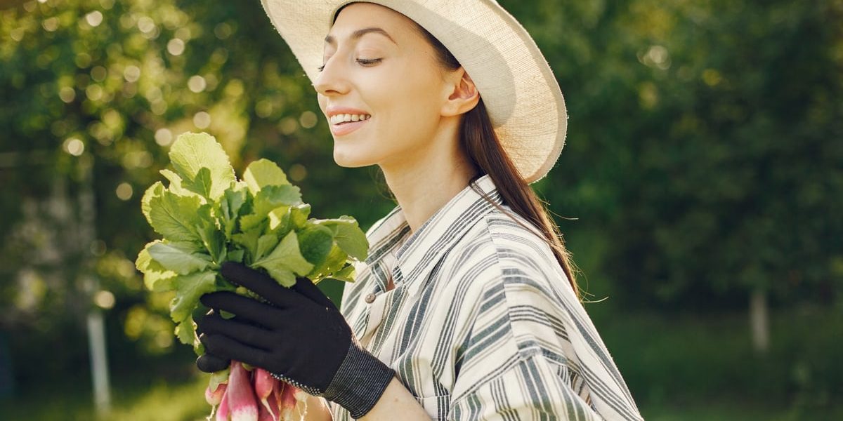 Happy woman enjoying a fresh harvest of radishes in a sunny garden.