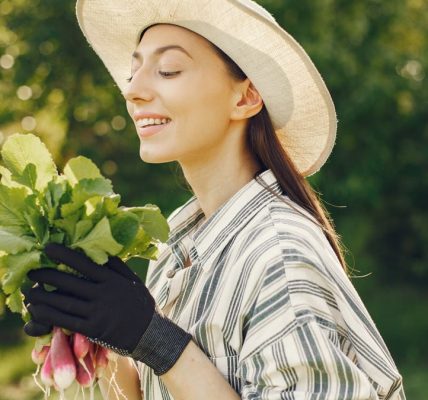 Happy woman enjoying a fresh harvest of radishes in a sunny garden.